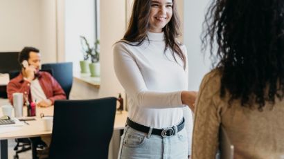 New employee smiling and meeting a coworker on her first day at the office