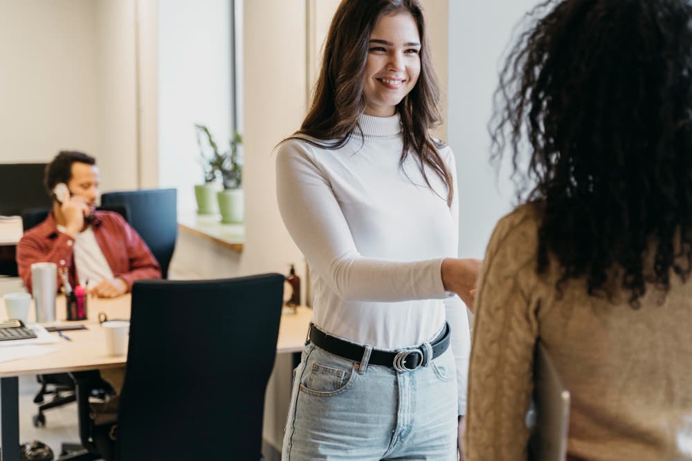 New employee smiling and meeting a coworker on her first day at the office