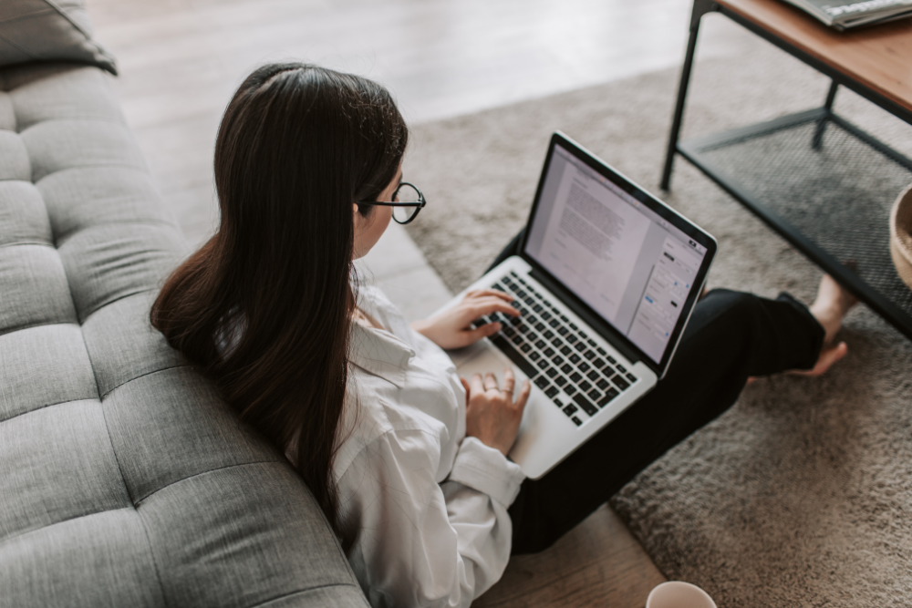 female woman working on her laptop while sitting on the floor at home