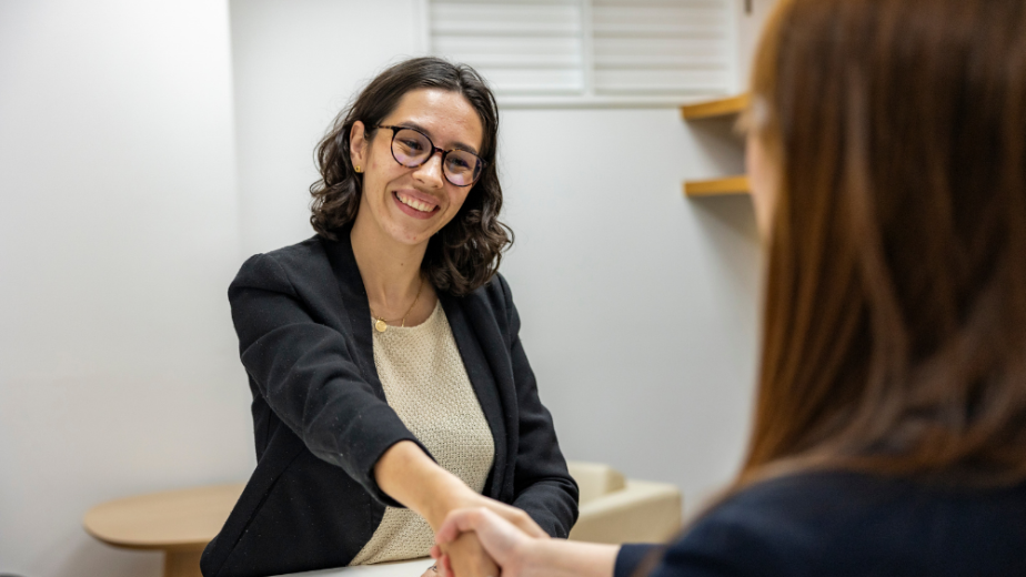 two female professionals shaking hands with one of the women smiling