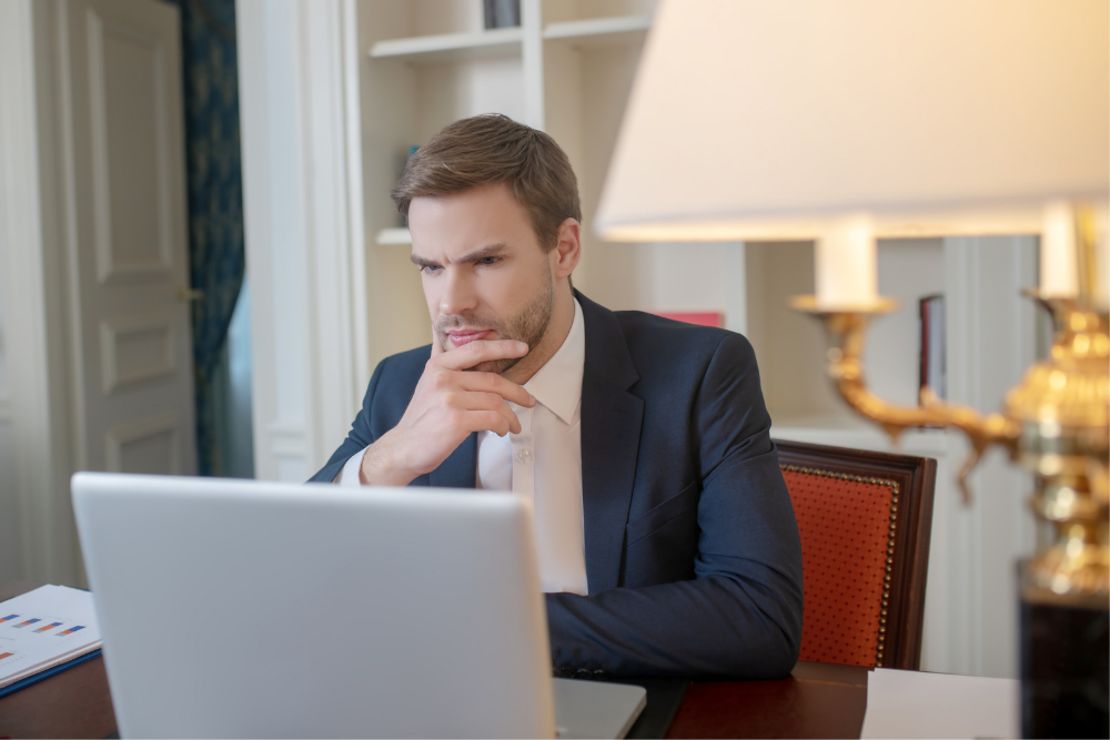 a man thinking and looking at his laptop in a room
